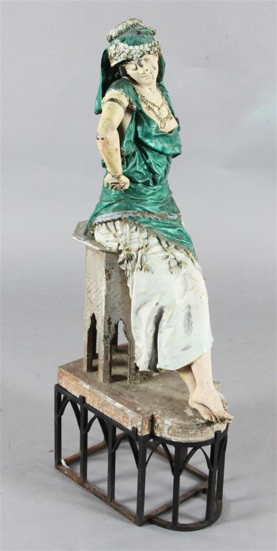 Manner of Louis Hottot. A painted spelter model of an Arab dancing girl leaning against a table, height overall 39in.